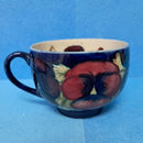 A Moorcroft Cup and Saucer in the Pansy Pattern by William Moorcroft