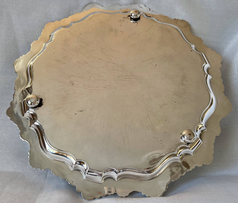 Large silver plated circular salver with shell and scroll border, raised on bun feet.